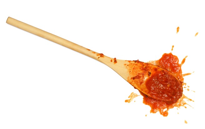 A wooden spoon dropped on the floor after stirring the tomato sauce.